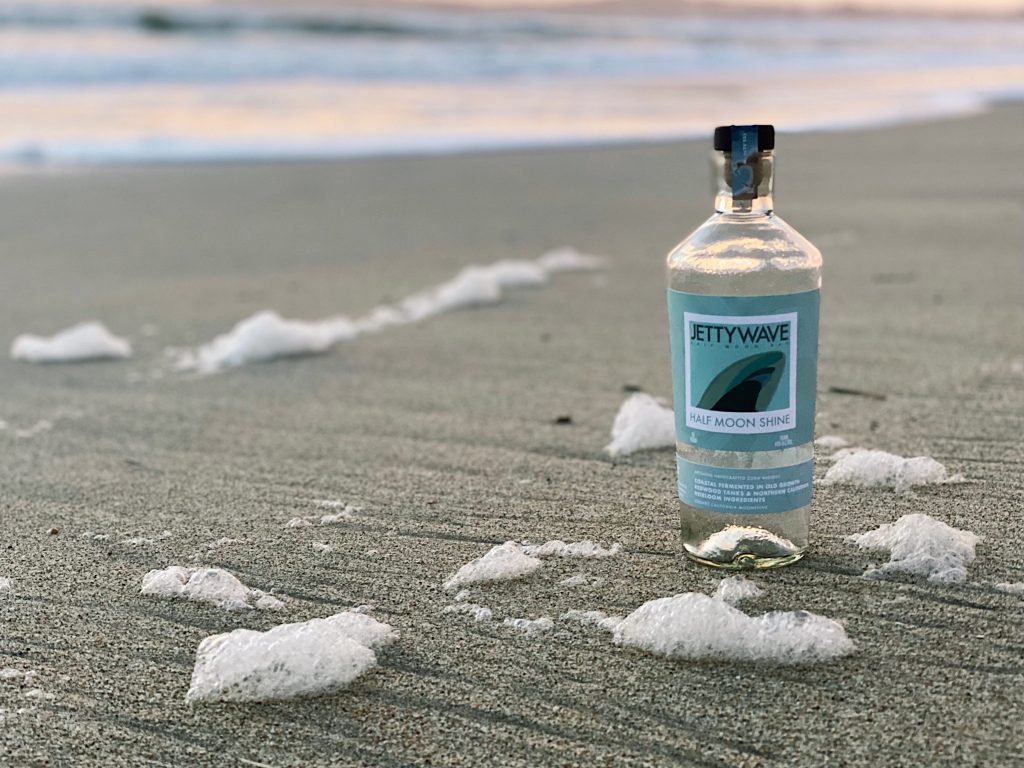a bottle of Half Moon Shine on the beach